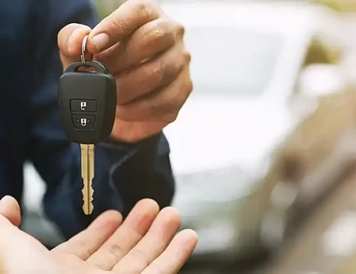 Pessoa entregando uma chave para outra, simbolizando a liberação de um carro reserva após sinistro