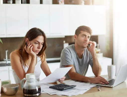 Casal analisando documentos em casa com expressão preocupada, representando a dúvida sobre a diferença entre seguro e proteção veicular