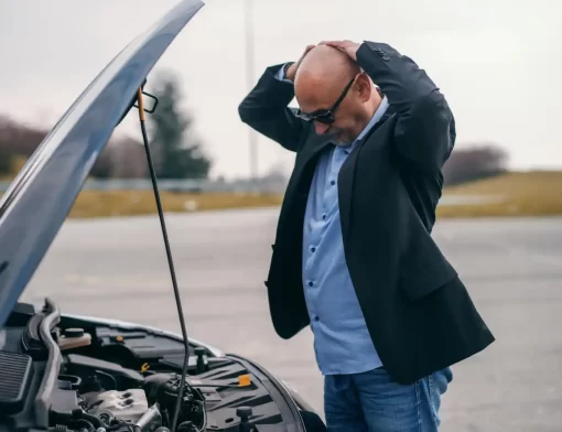Homem preocupado em frente a um carro com o capô aberto, representando situação de pane e dúvida se o seguro cobre motor fundido