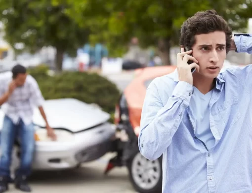 Motorista preocupado ao telefone após acidente de carro, representando a importância do seguro contra terceiros para cobrir prejuízos