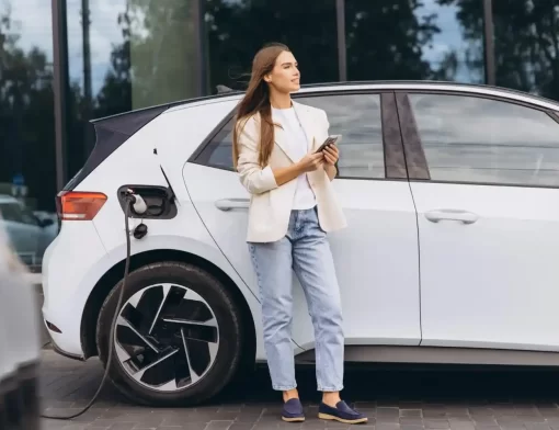 Mulher ao lado de carro elétrico em carregamento, destacando pneu para carro elétrico com foco em eficiência e segurança.